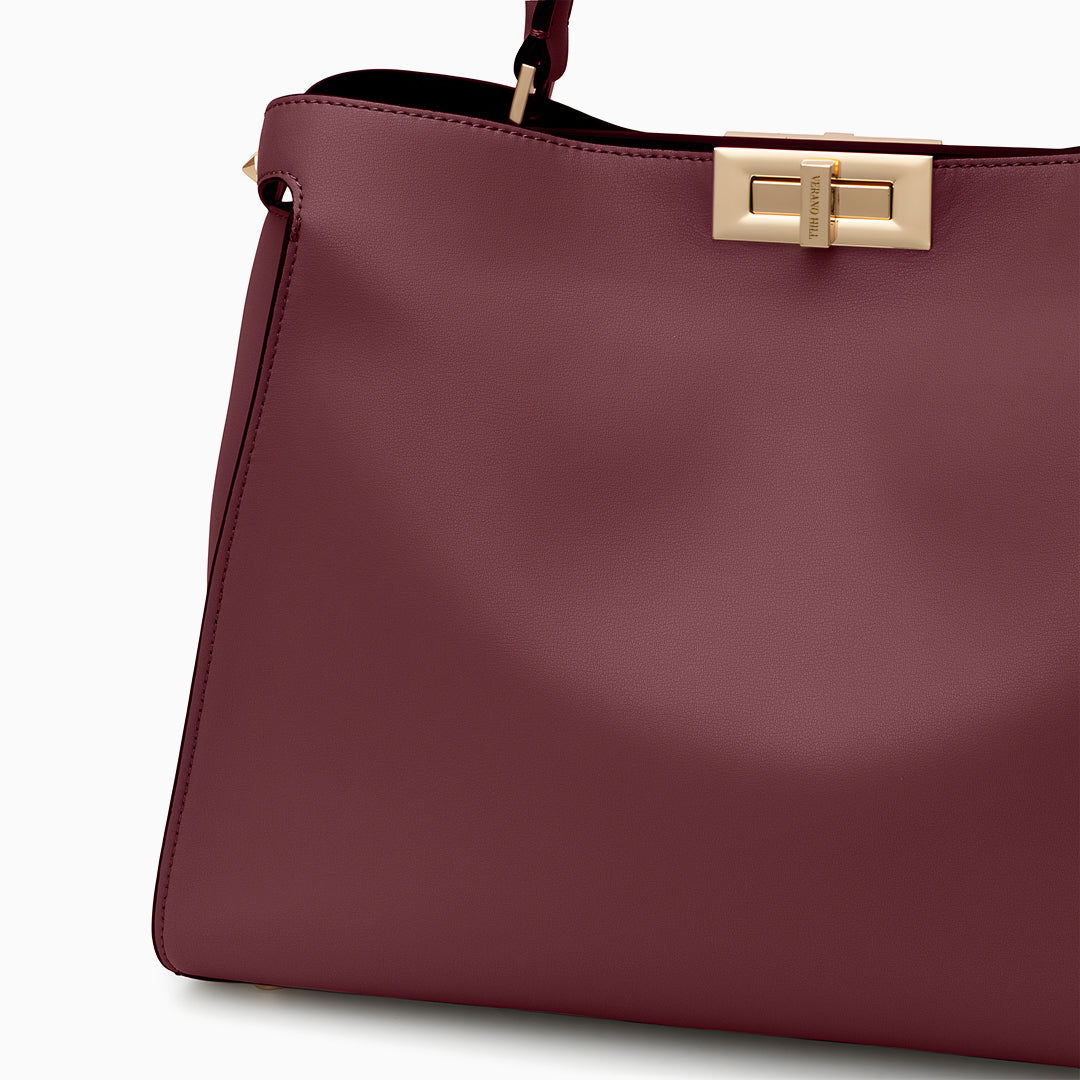 Maroon handbag with a gold clasp on a white background