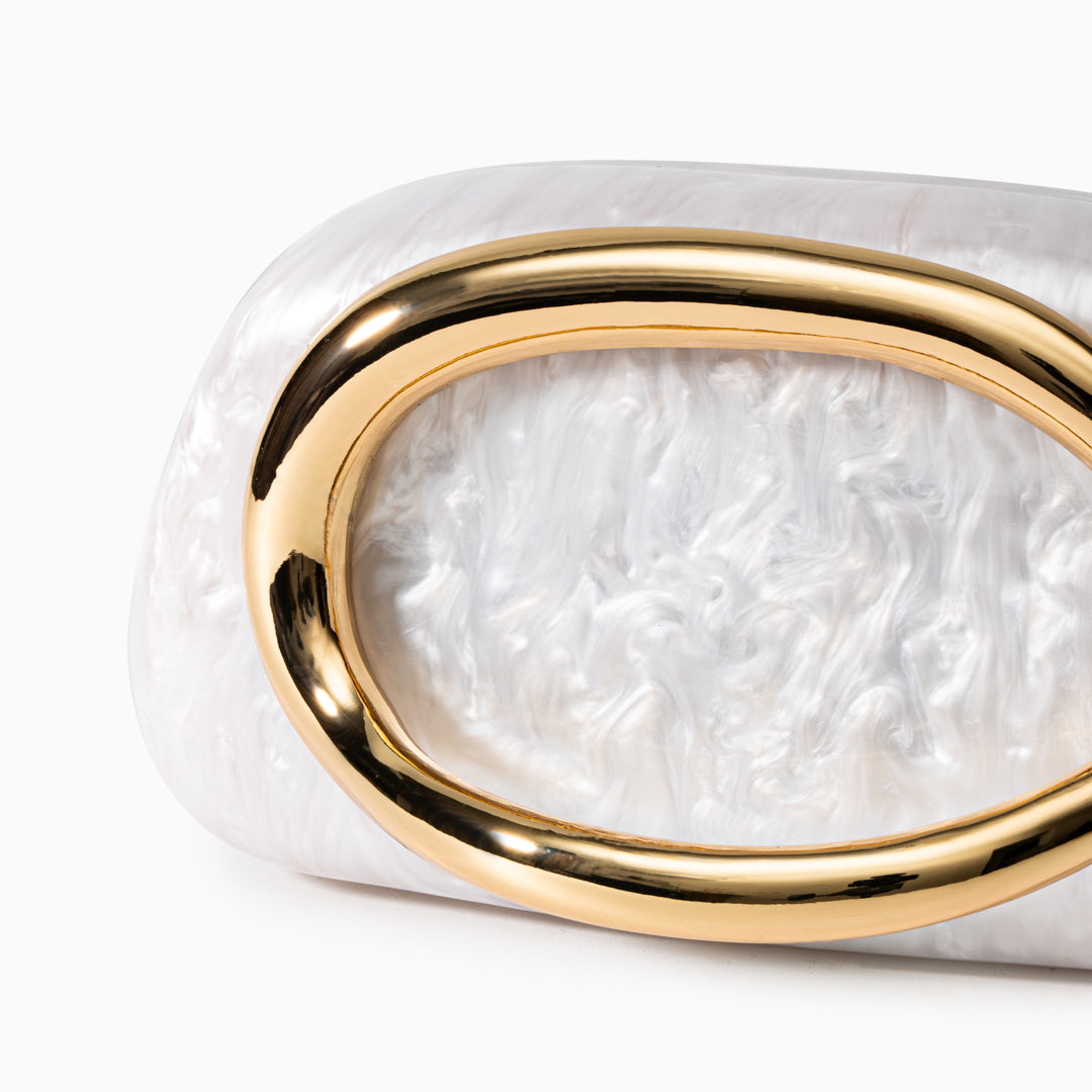 Elegant sculptural gold clutch bag with a pearlescent acrylic finish on a white background