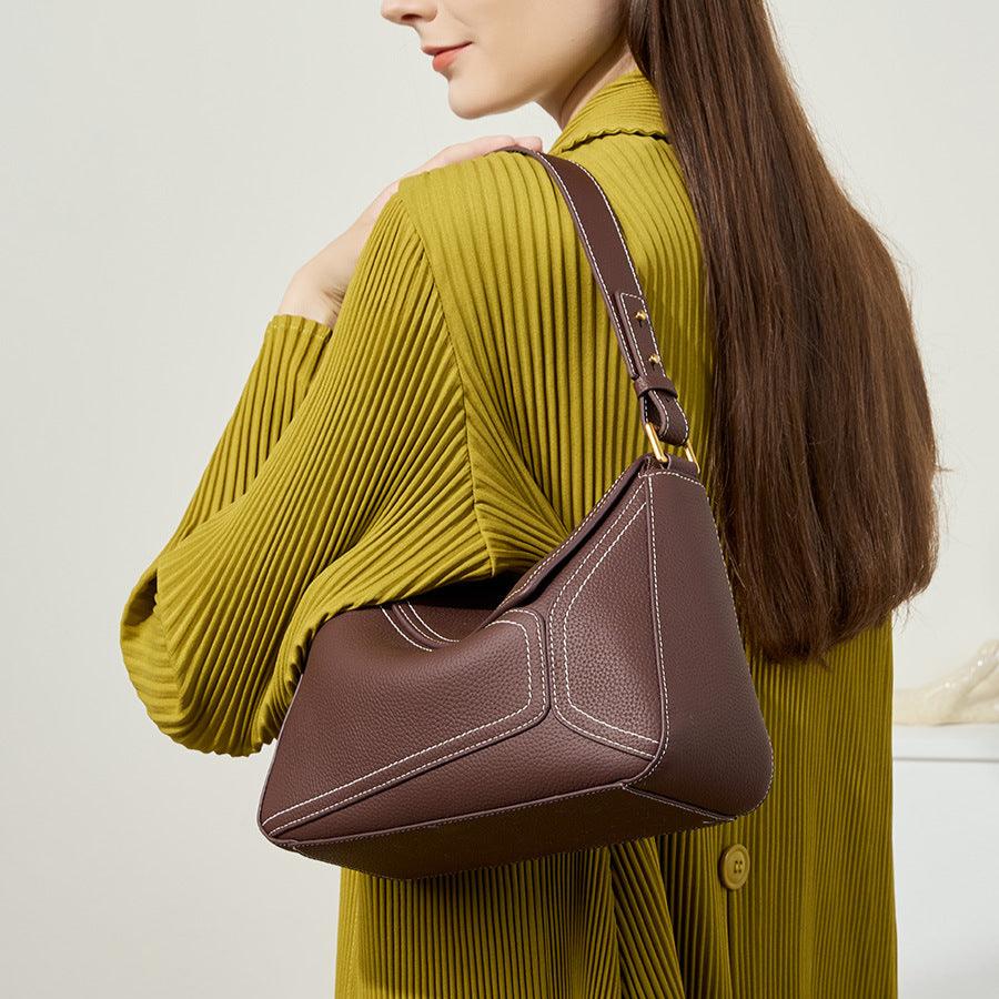 Woman holding a brown handbag against a plain background
