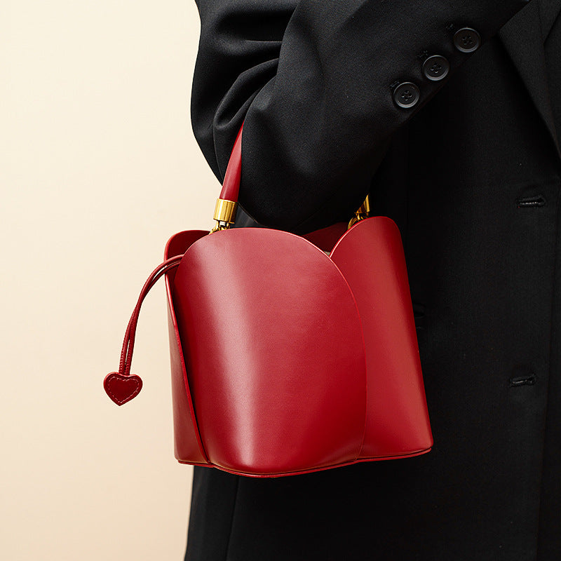 Burgundy bucket handbag with a heart-shaped closure. 1