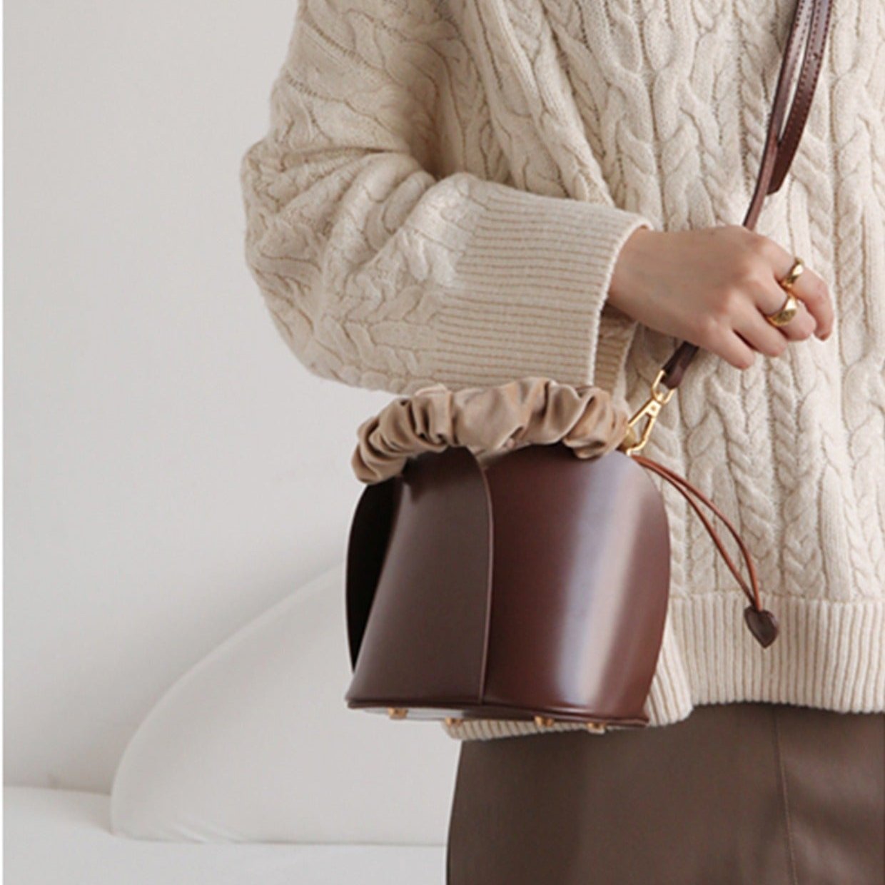 A burgundy bucket handbag with a heart-shaped closure, featuring a stylish design and elegant handle. 7