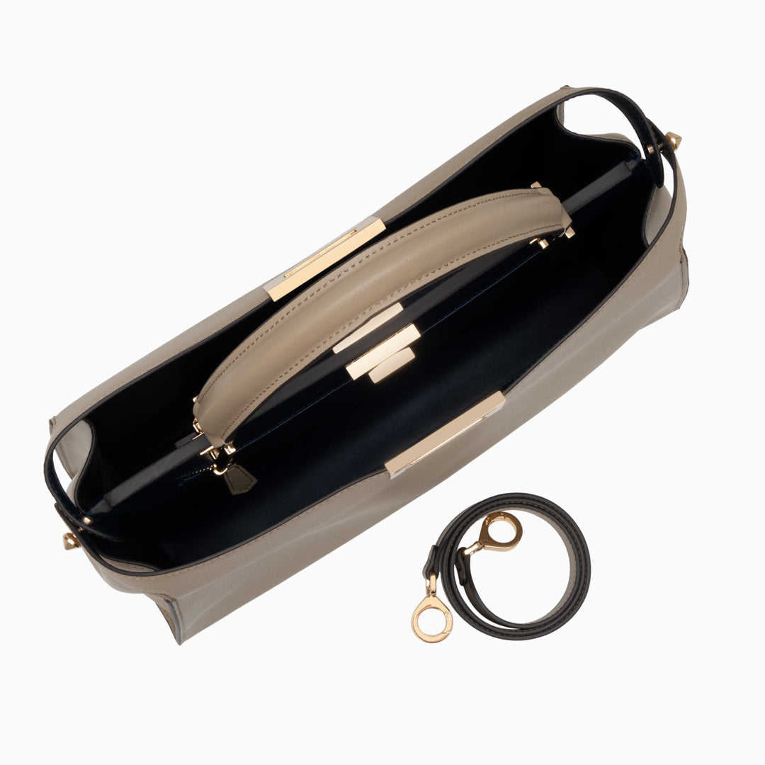 Top view of beige handbag with gold accents on a white background