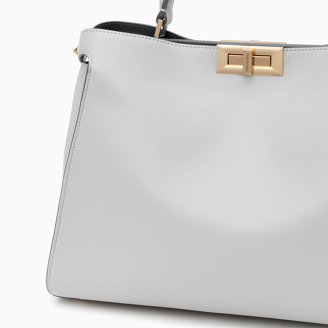 White handbag with a gold clasp on a white background