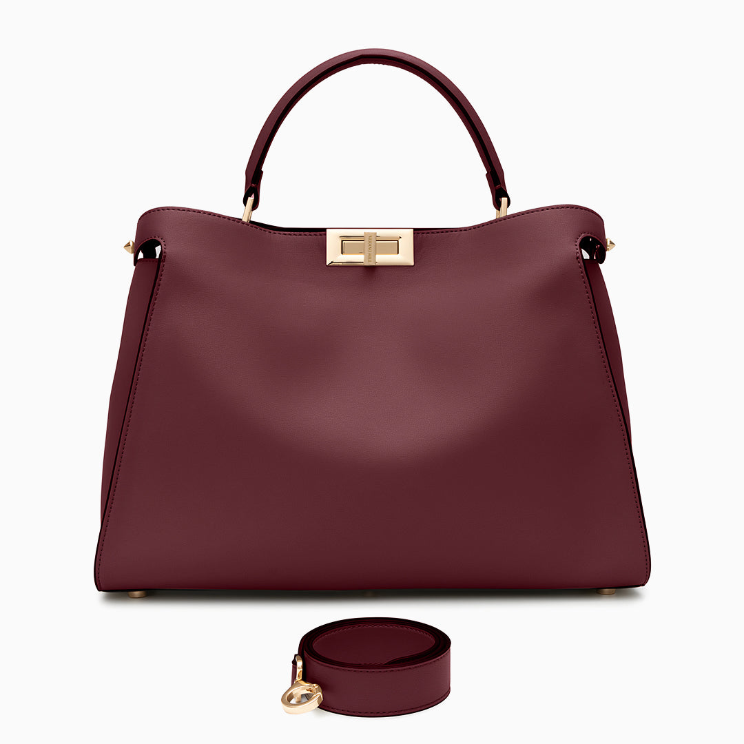 Maroon handbag with gold clasp and matching round pouch on a white background