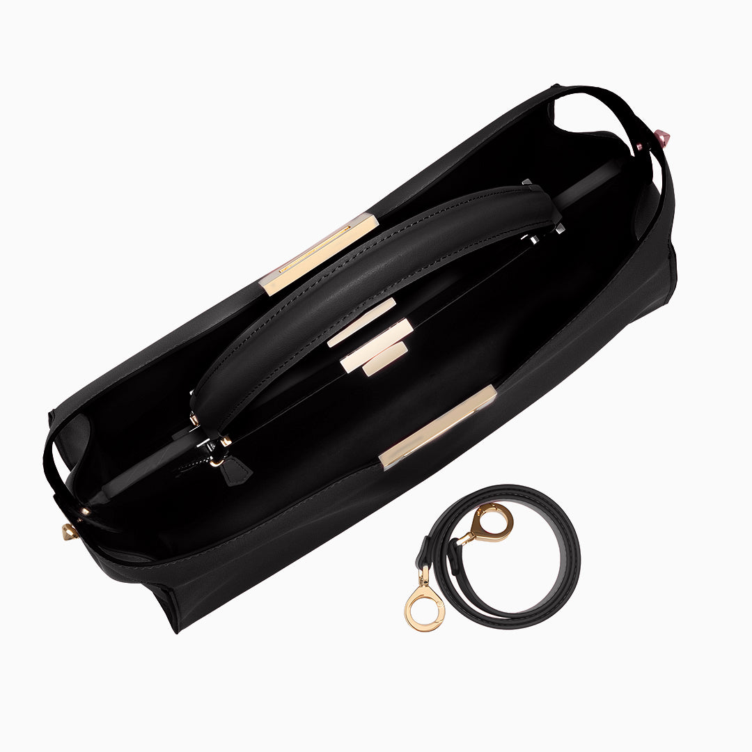 Black handbag with gold accents and a matching strap on a white background