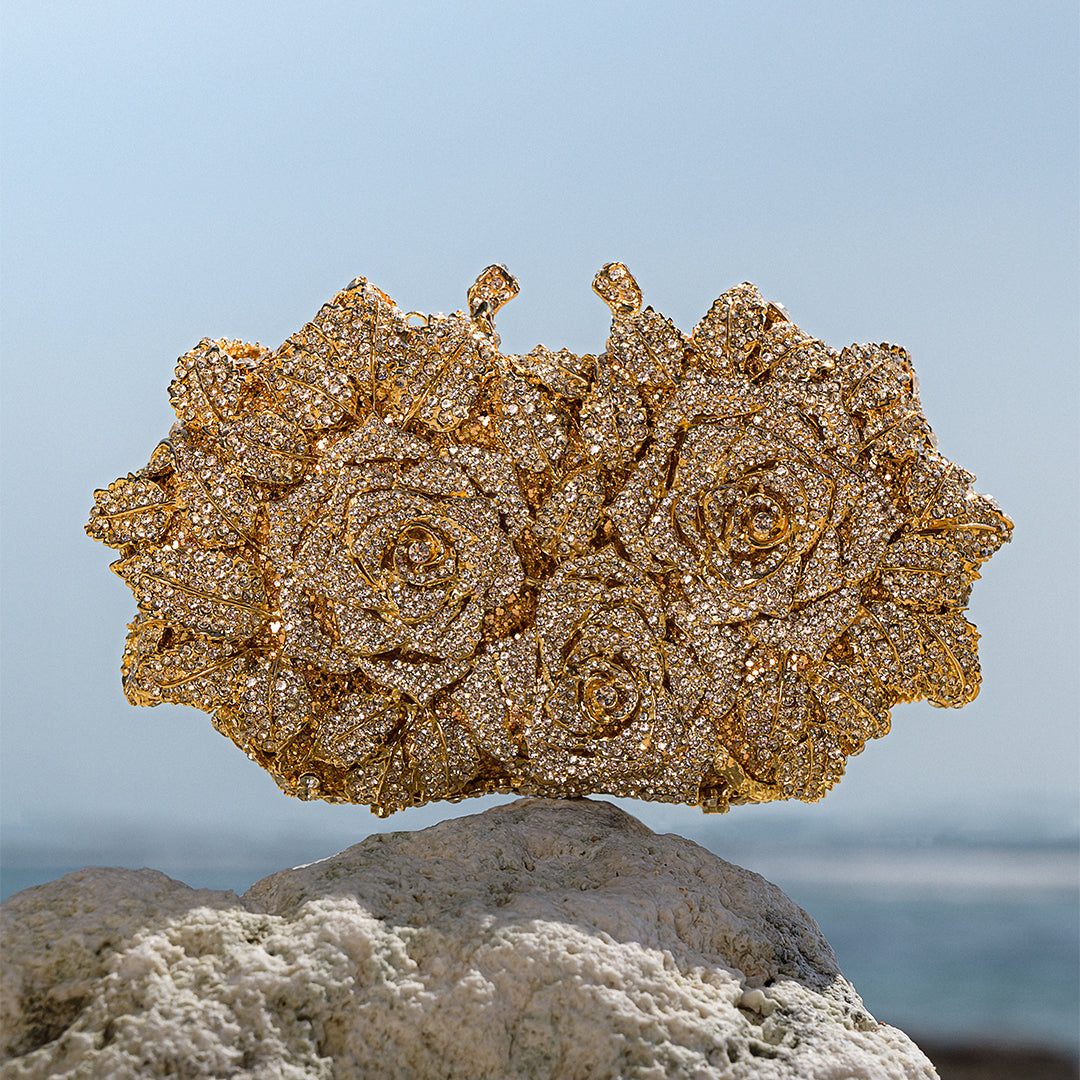 Gold floral jewelry piece on a rock with a blurred natural background