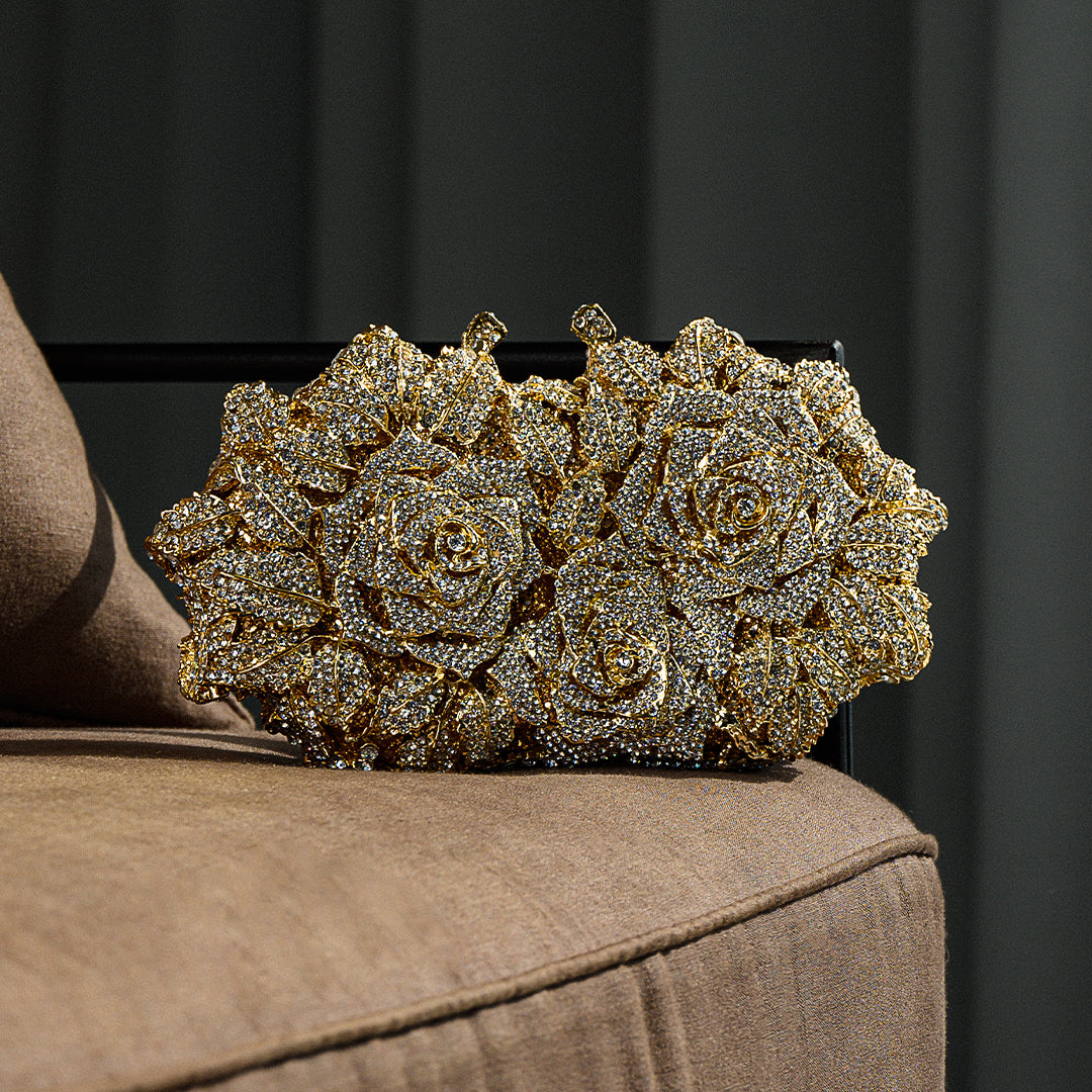 Gold floral clutch on a brown surface with a dark background
