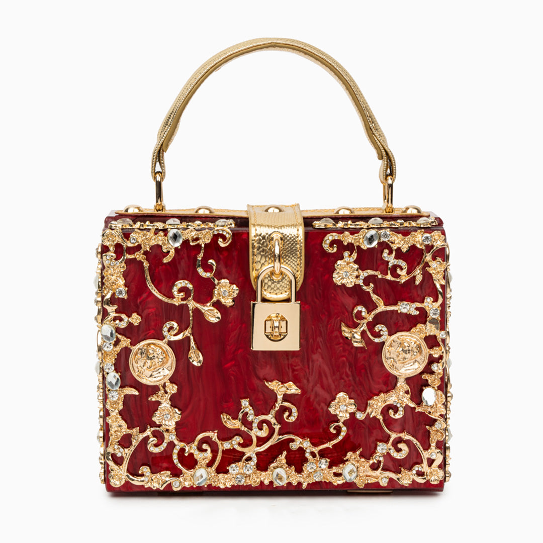 Red handbag with gold intricate designs and a gold lock on a white background