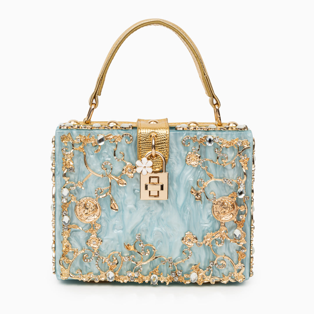 Decorative handbag with gold embellishments on a white background